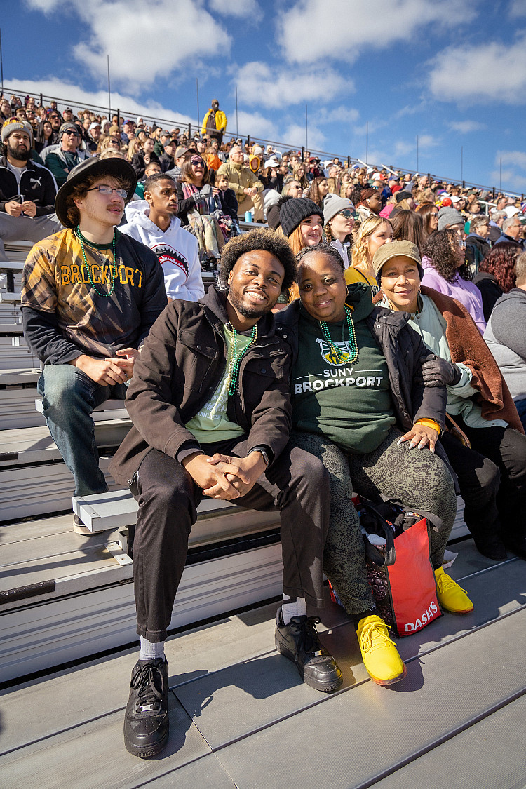 Brockport student with their mother posing in front of the Homecoming crowd