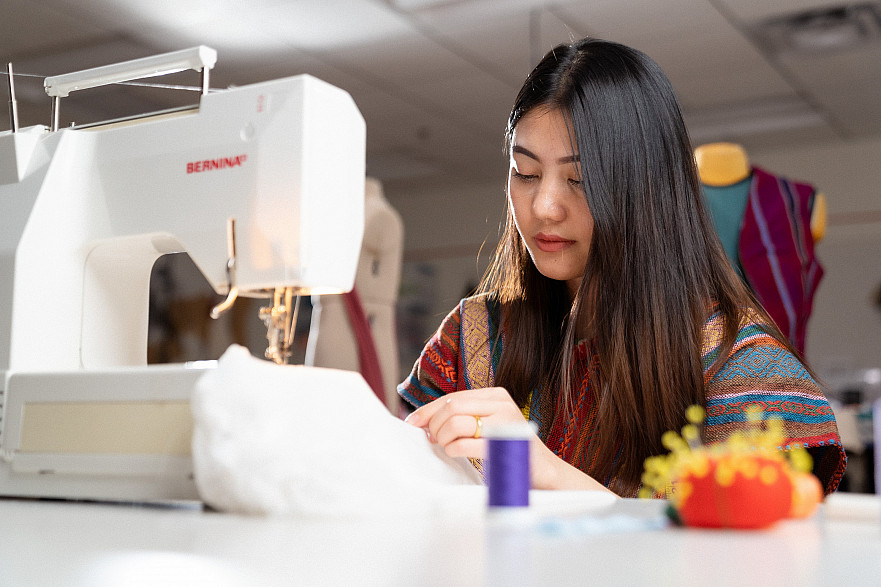 Student sitting at a table and sewing