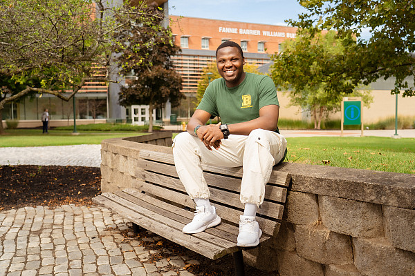 International student and nursing major, Precious Cyril, sitting on a bench near the Special Olympics Fountain and smiling.