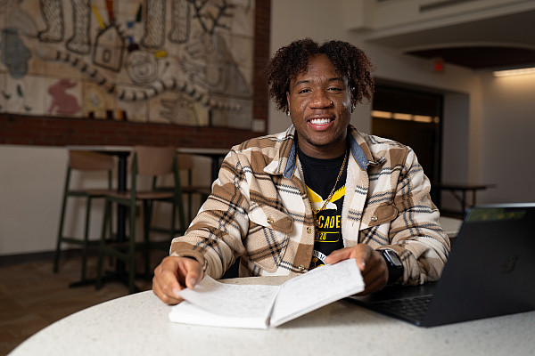 DaJuan Jackson sitting at a table with a notebook out and smiling.