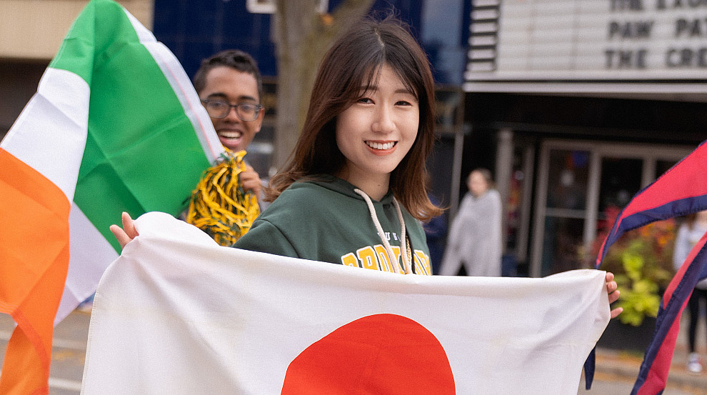 International student walking with a flag at the homecoming parade