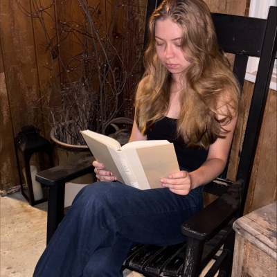 Tess Neilans reading a book on a rocking chair