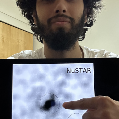 Shishir Chhetri pointing at an x-ray image of a black hole region on his laptop