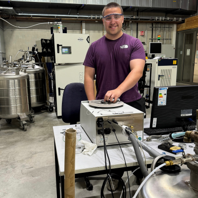 Caleb Janikas wearing protective glasses in a lab filled with various pressurized containers
