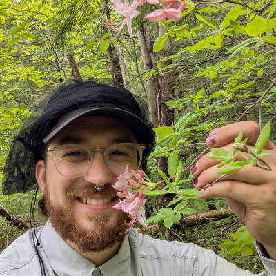 Justin Montione smiling and showing a blooming flower from a plant