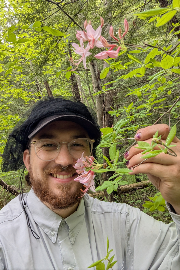 Justin Montione smiling and showing a blooming flower from a plant
