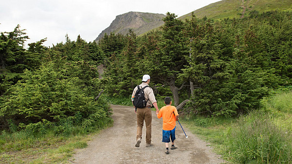 Counselor guiding a blind camper on a hike in Alaska