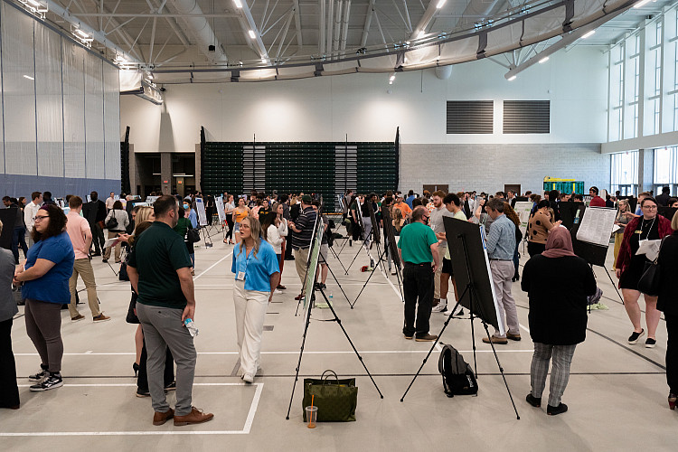 Students, faculty, and staff talking to one another on Scholars Day with a bunch of posters showing their work and research.