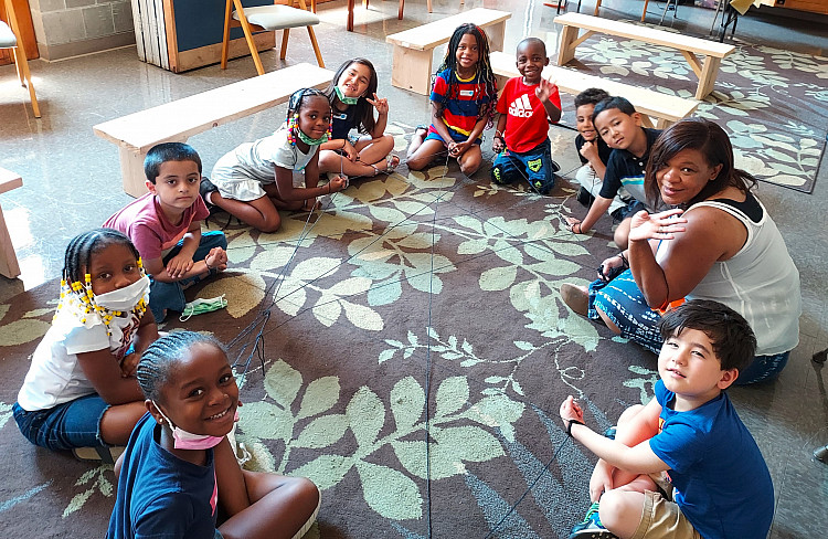 Group of children sitting in a circle in the middle of a classroom