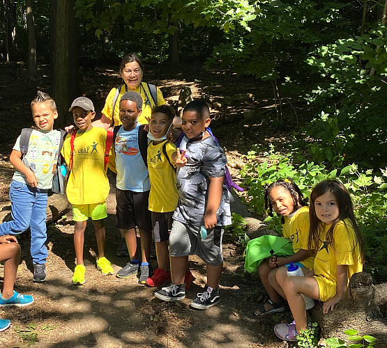 Group of children and a staff posing for the camera on an outdoor trail