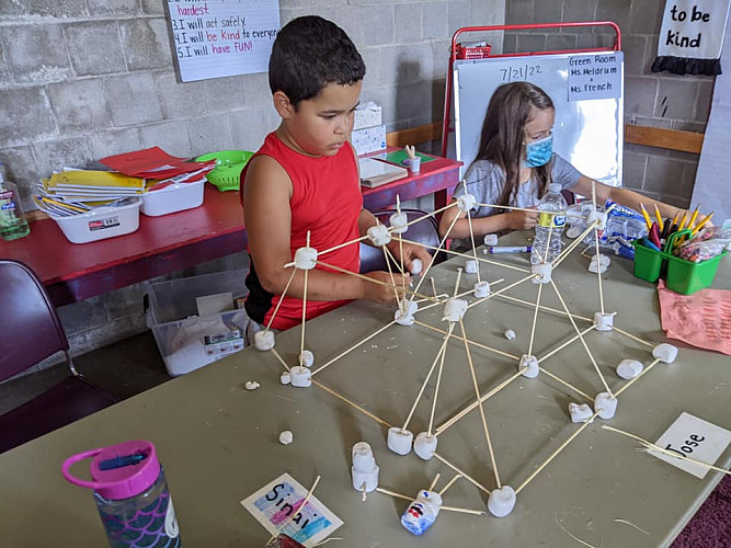 Children constructing a makeshift building out of marshmallows and sticks