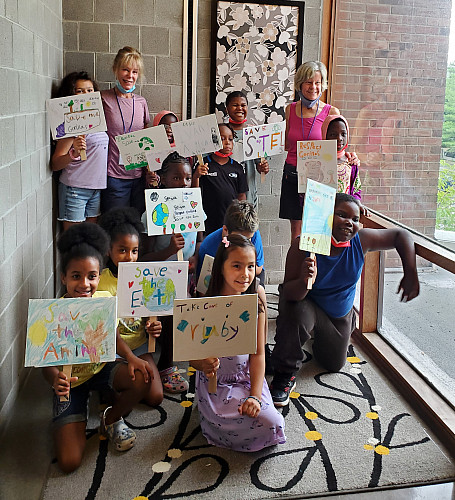 Group of children holding up their drawings in a classroom