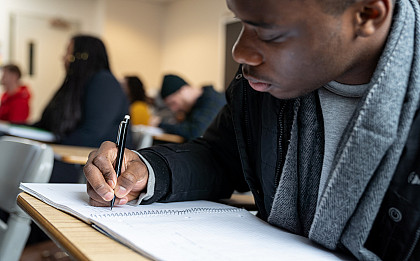 student writing on a notepad