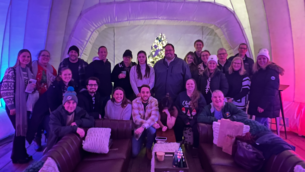 Advancement & Communications staff posing for a group photo in an igloo at the ROC Holiday Village