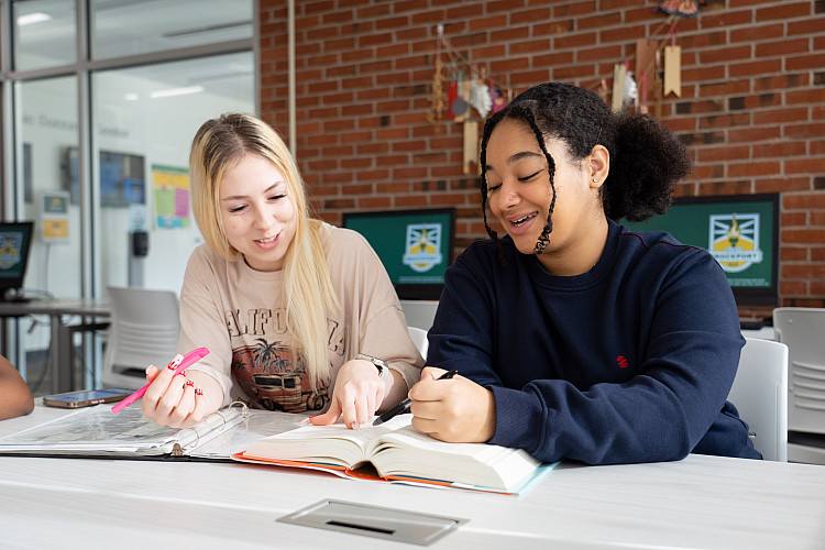 Two Fannie Barrier Williams Scholars look over a textbook together.