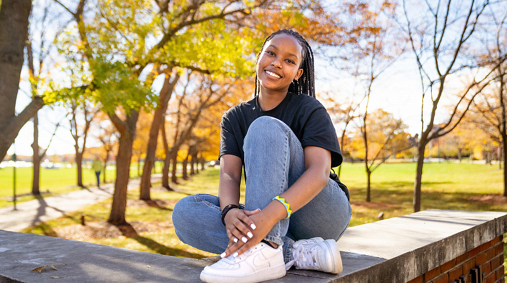 student poses on brick platform on campus