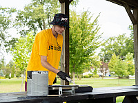 One student volunteer painting a picnic table at a local park