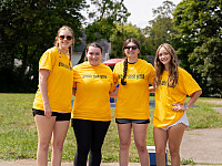 Four students wearing yellow t-shirts standing and smiling during Saturday of Service
