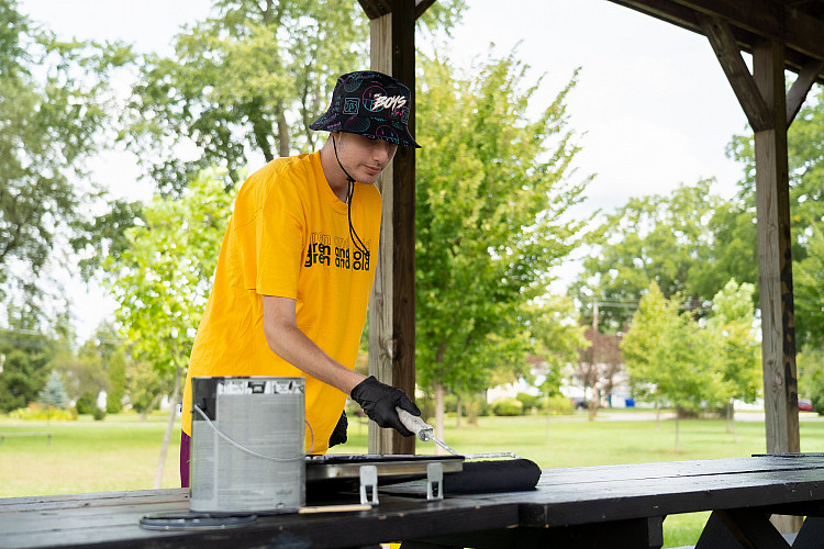 One student volunteer painting a picnic table at a local park