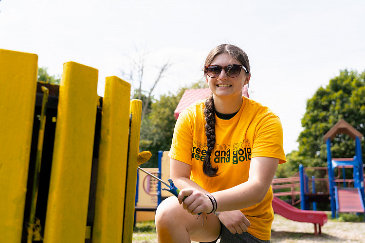 Student smiling painting during Saturday of Service