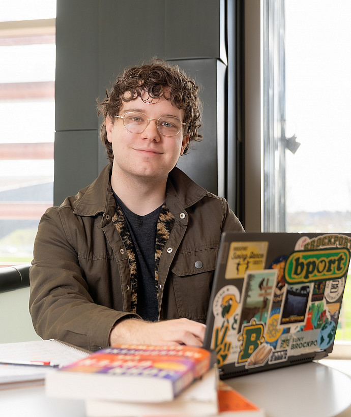 Brockport student sitting at table working on laptop.