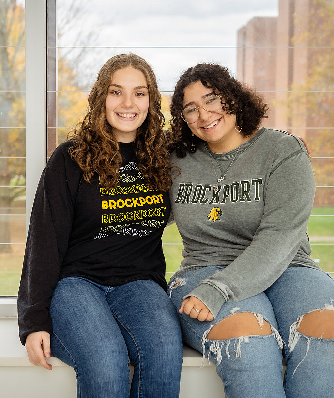 Two Brockport students sitting on ledge.