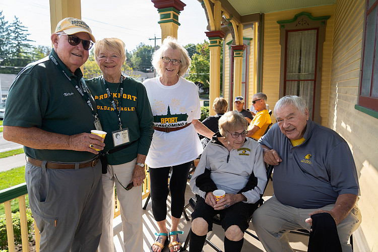 Group of people sitting on porch of Alumni House