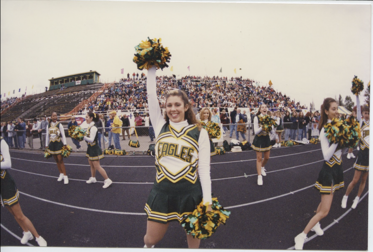 Cheerleader on sidelines at football game.