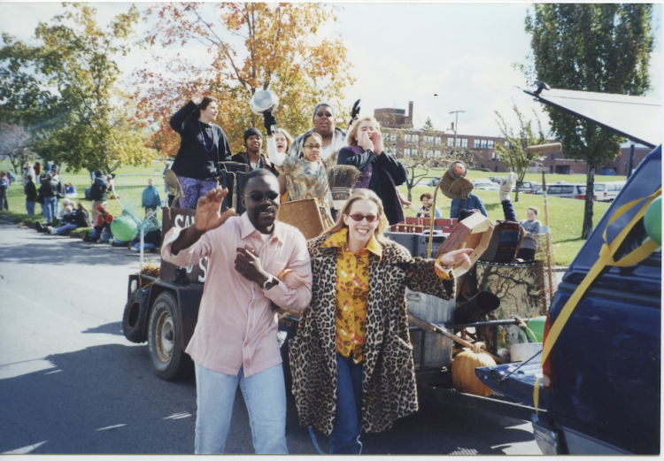Group of people waving and walking in parade.