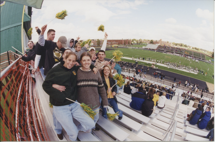 Group of people in bleachers at football game.