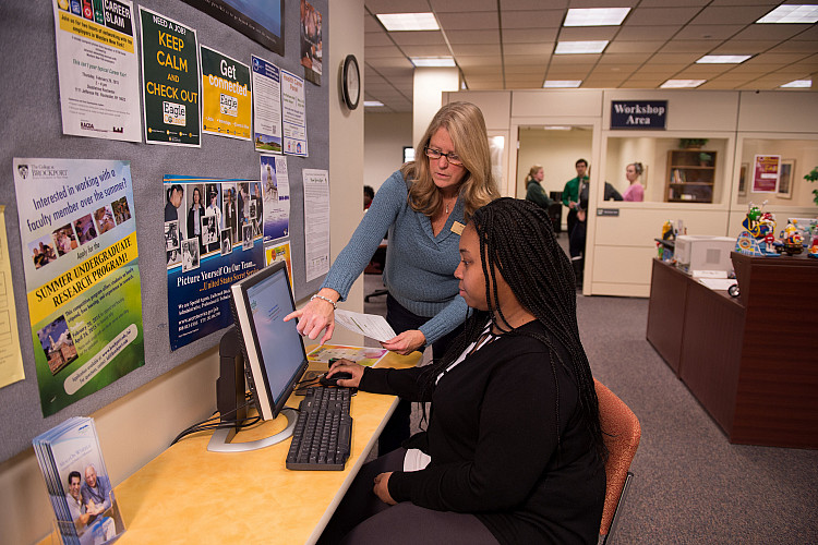Two people looking at computer screen.