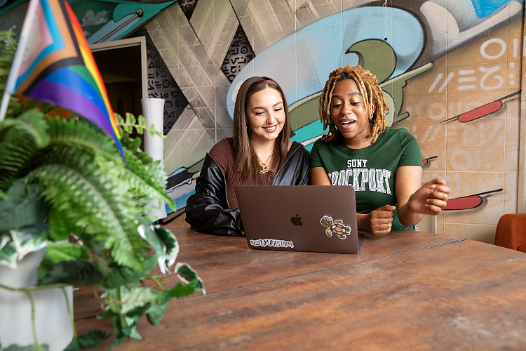 Two Brockport students looking at laptop.
