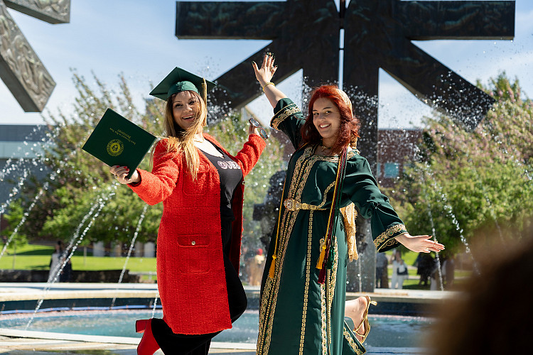 Two women in front of fountain after commencement.