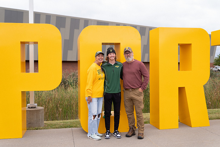 family poses with BPORT letters at homecoming