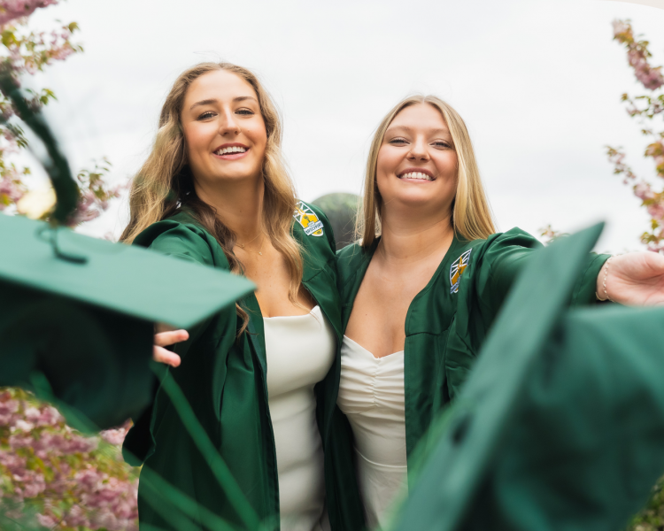 cap and gown graduates throwing their caps at the camera