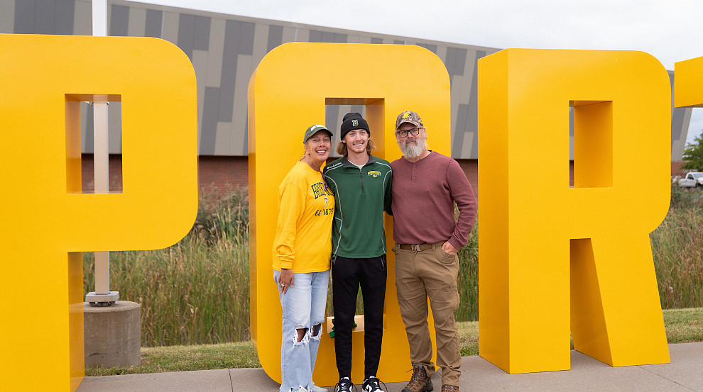 family poses with BPORT letters at homecoming
