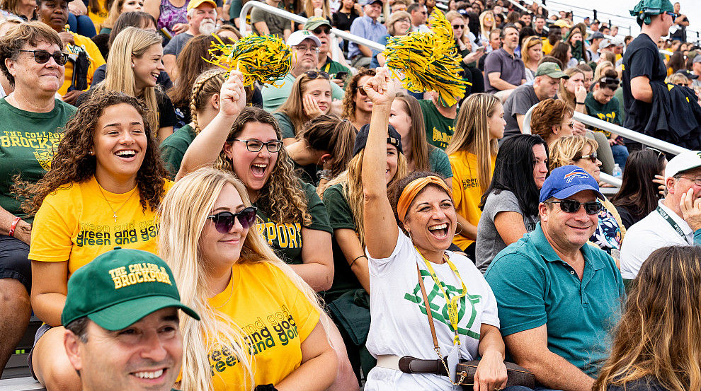 People sitting in bleachers waving poms poms.
