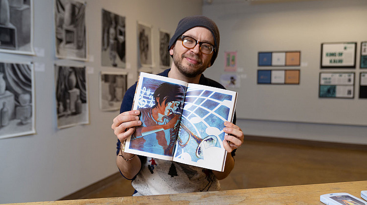 David Chisholm holding his graphic novel Enter the Blue
