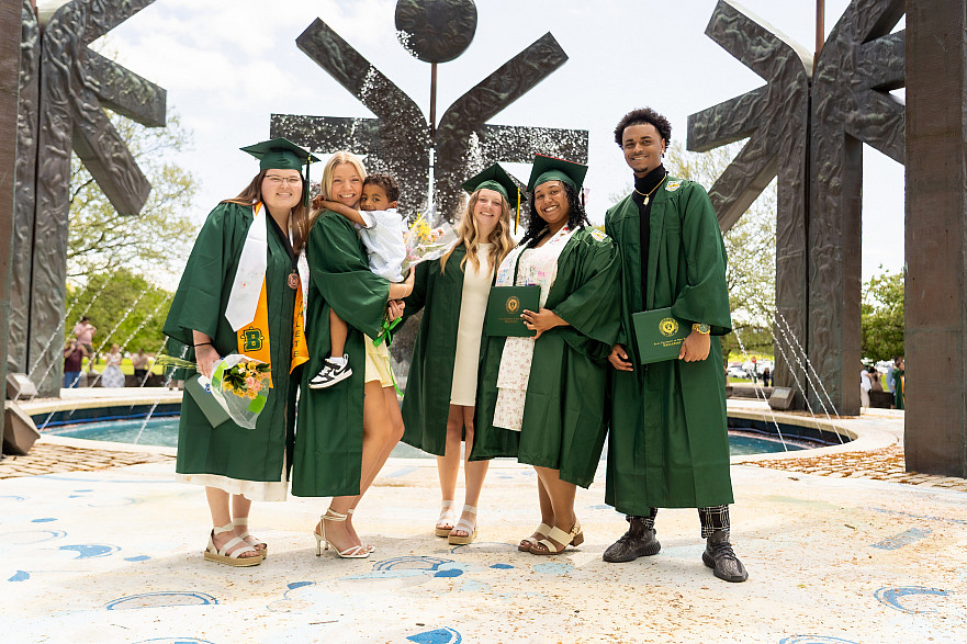 Five students posing for a group photo at the Special Olympics Fountain on campus on Commencement Day.