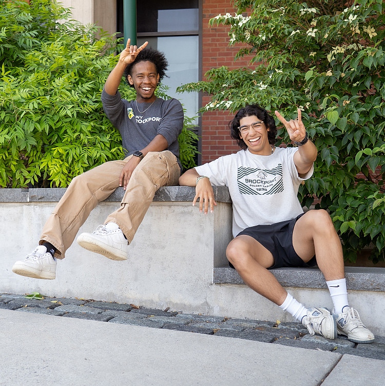 Two SUNY Brockport Orientation Leaders posing for a photo on the steps of a campus walkway.