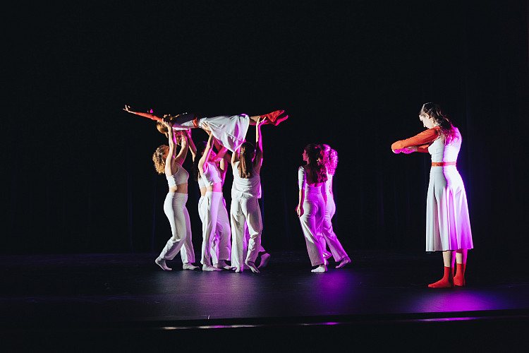 dancers on a stage lifting a dancer in the air