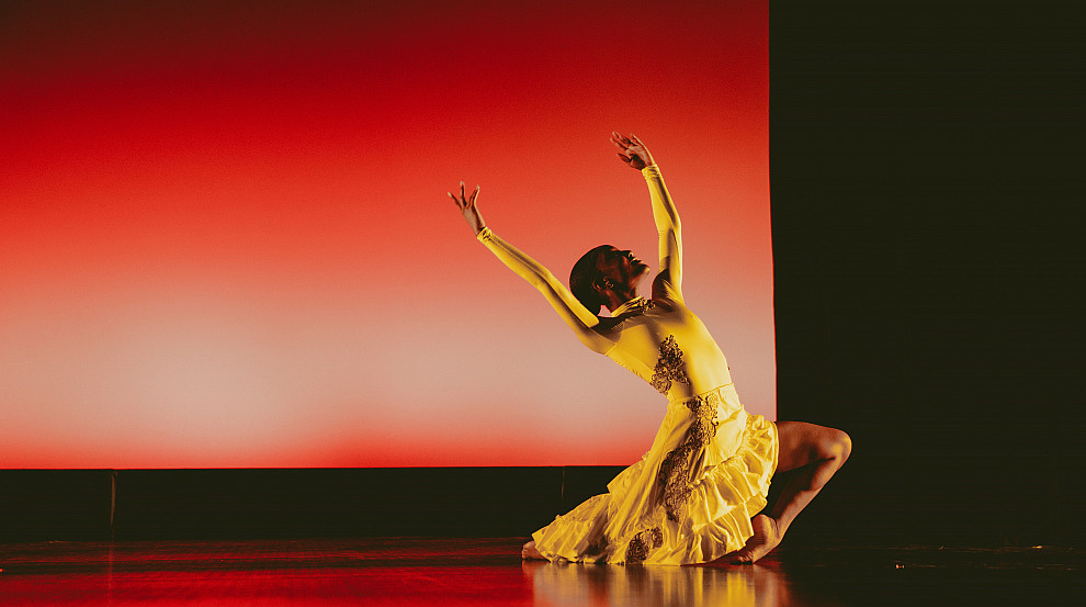 Student dancing on stage in a yellow costume 