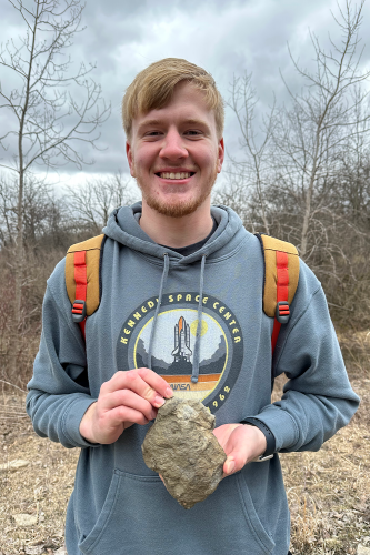 Earth Science student holding up a large rock