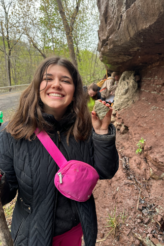Earth Science student smiling and holding up a rock