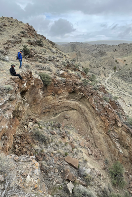 Geology students sitting and standing at the edge of a cliff