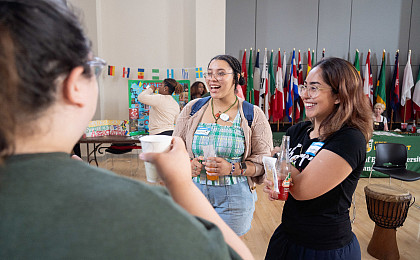 Students talking at the Multicultural Mixer on campus with flags in the background