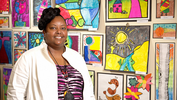 School administrator poses in front of a wall of children's artwork