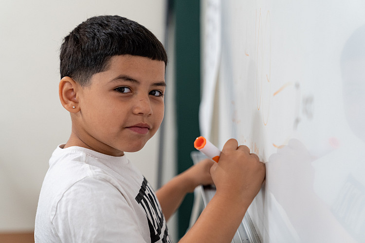 Young child writing on a white board