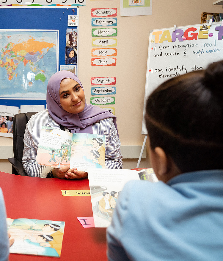 teacher talking with two students in an elementary classroom