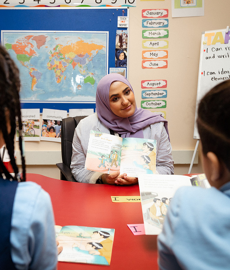 teacher talking with two students in an elementary classroom